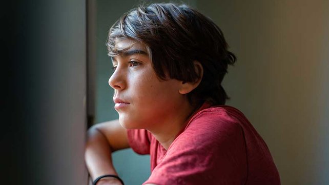 Latinx youth looking out window