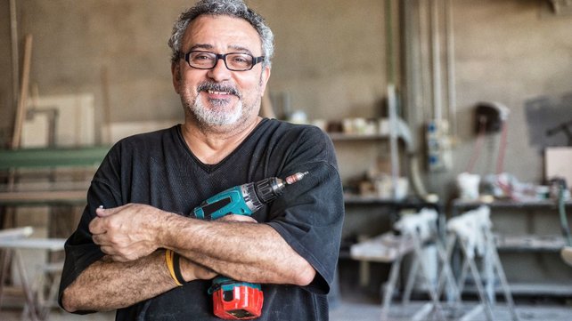Man in garage smiling and holding drill