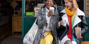 Two young adults laughing outside cafe